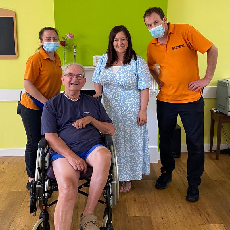 A care home resident in a wheelchair, with Amy and two staff members