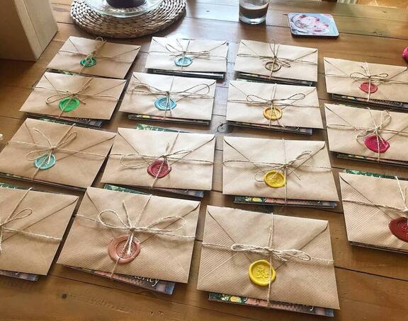 A table covered in brown envelopes each with a colourful wax seal, with a brown string bow tying a CD underneath. Ready to send to care homes.